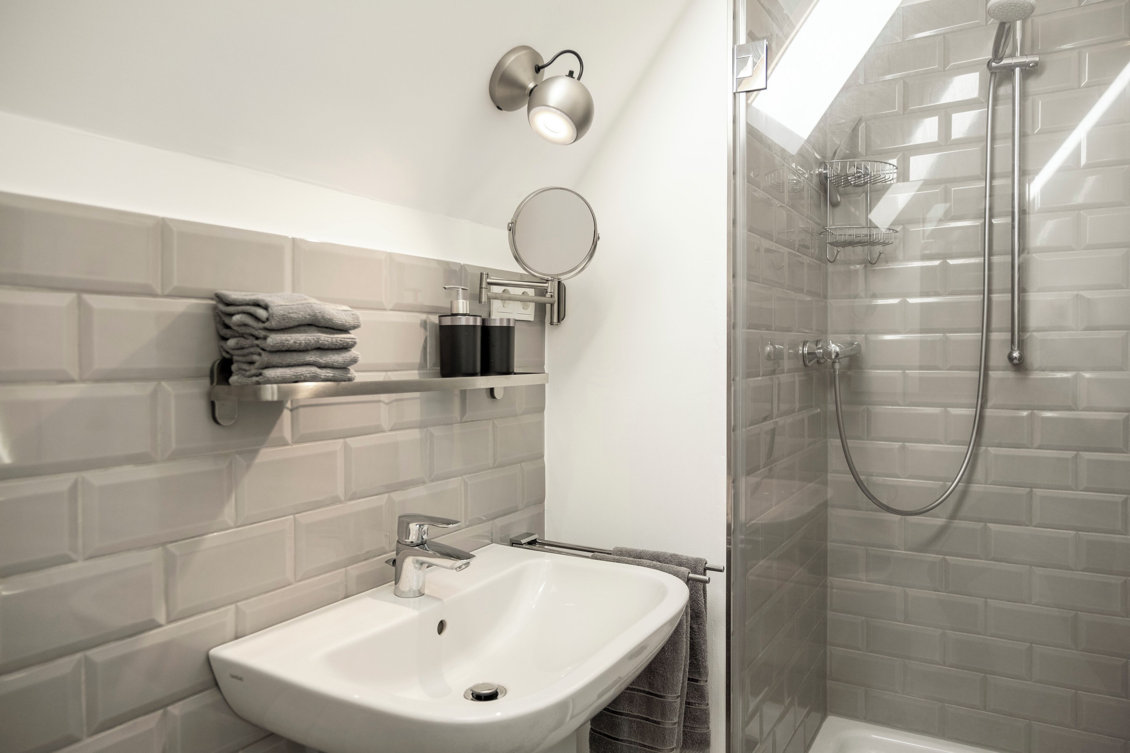 Een moderne badkamer met een wit wastafelmeubel, een douche met glazen wand en een handdoekhouder.