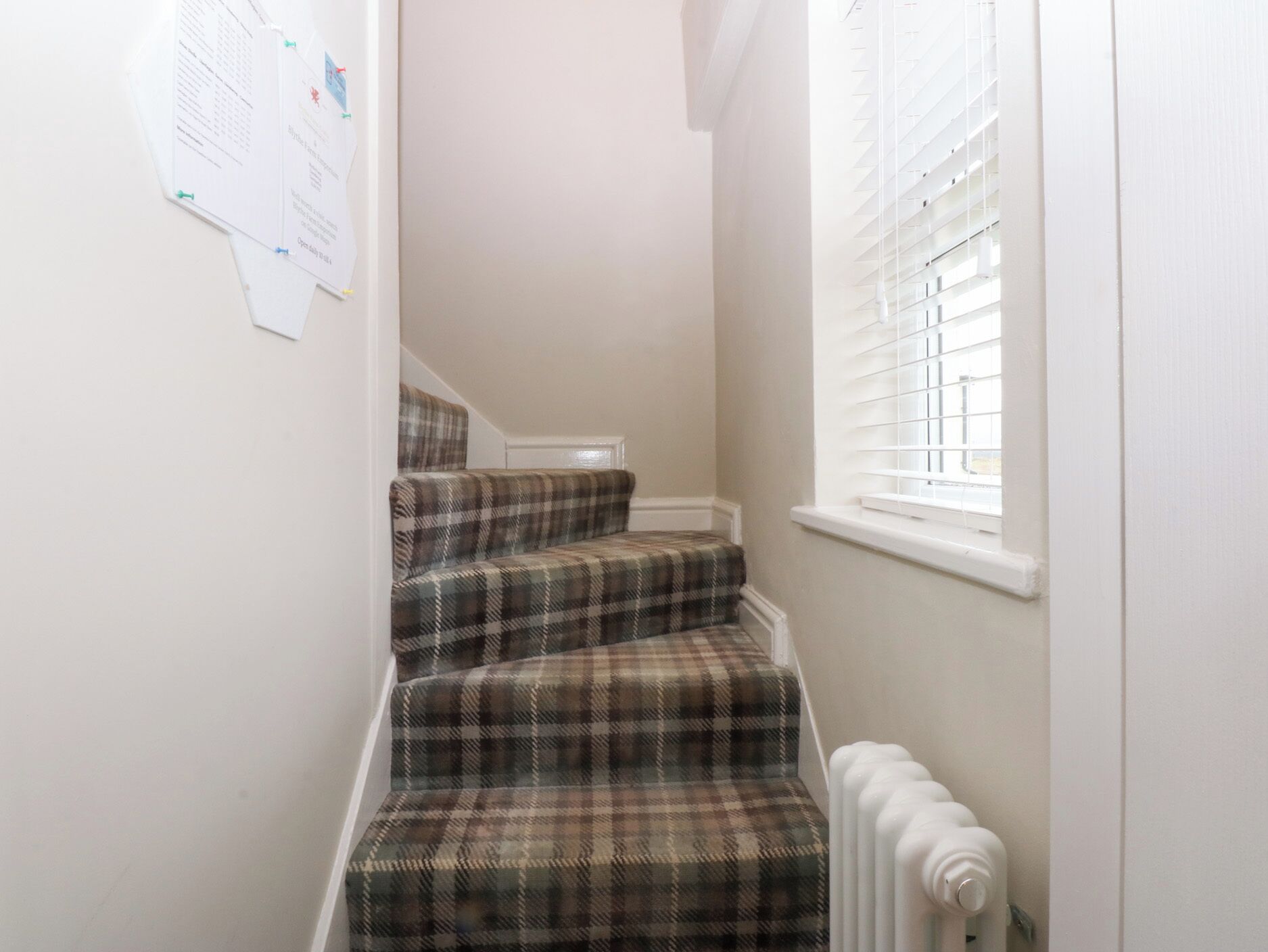A staircase with plaid carpeted steps leading to a landing.