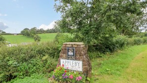 A stone sign with 'Appleby' and 'County Town of Westmorland' written on it, surrounded by greenery and flowers.