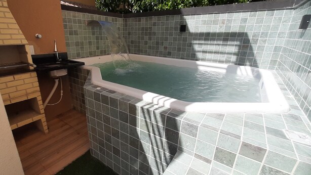 A hot tub with tiled walls and a wooden bench. - Casa Janaína (Camaçari)