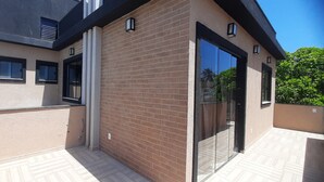 A modern building with a brick facade, large windows, and a glass door. - Casa Janaína (Camaçari)