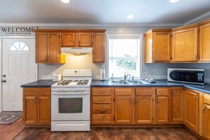 A kitchen with wooden cabinets, a stove, a microwave, and a sink.