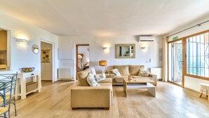 A spacious living room with a large sofa set, a coffee table, and a dining area with a glass table and chairs.
