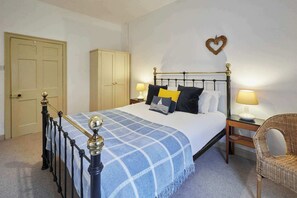 Ein Schlafzimmer mit Bett, Nachttischen, einem Sessel, einem Kleiderschrank und einer herzförmigen Dekoration an der Wand.