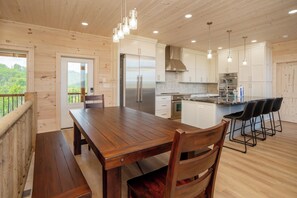 A wooden interior with a dining table, chairs, a kitchen area, and a balcony with a railing.