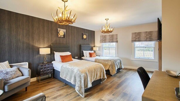 Een moderne slaapkamer met twee bedden, een slaapbank, een eettafel en een televisie.