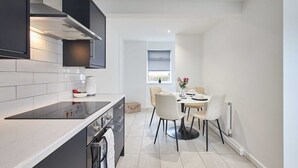 Une cuisine moderne dotée d’un îlot central, de meubles blancs et d’un coin repas avec une table ronde et des chaises.