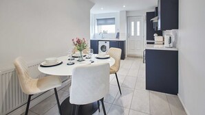 Une cuisine moderne avec un coin repas, comprenant une table ronde, des chaises et un lave-linge encastré.