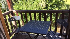 Una terraza de madera con una mesa de metal y dos sillas.