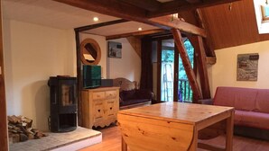 Una habitación acogedora con una mesa de madera, una chimenea, un sofá y un armario de madera.