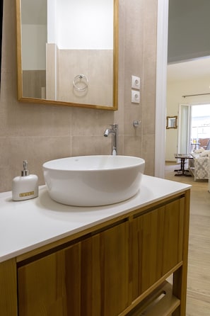 A bathroom with a round white sink, wooden vanity, and a mirror. - Casa Tsipa (Corfu)