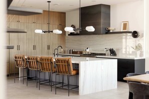 A modern kitchen with a large island, bar stools, and a built-in stove. - Scottsdale Retreat - Pool, Outdoor Grill, Firepit (Scottsdale)