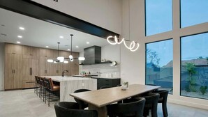 A modern kitchen with a central island, bar seating, and a dining area with a large window. - Scottsdale Retreat - Pool, Outdoor Grill, Firepit (Scottsdale)