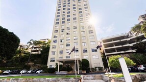 A tall, multi-story hotel with a flagpole, a covered entrance, and a parking area. - Harbourside #53 (McMahons Point)