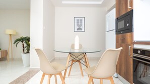 Una cocina moderna con una mesa de vidrio, dos sillas, un microondas y un horno.