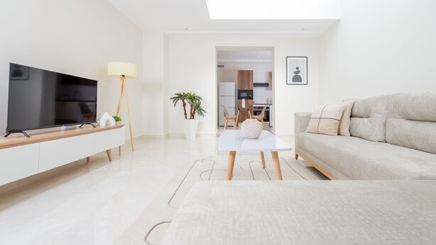 Una sala moderna con televisor de pantalla plana, un sofá, una mesa de centro y una zona de comedor con sillas y una mesa.