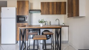 Una cocina moderna con armarios de madera, microondas integrado, lavavajillas y un fregadero. Hay dos taburetes en la isla.
