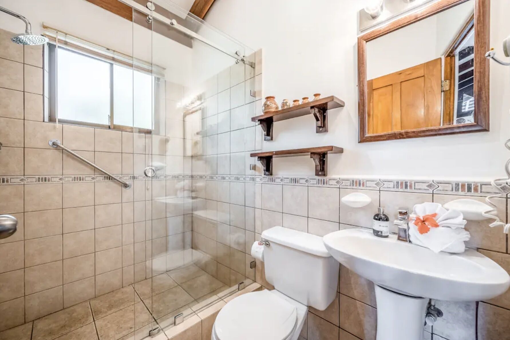 Un bagno con box doccia in vetro, un water e un lavandino con specchio sopra.