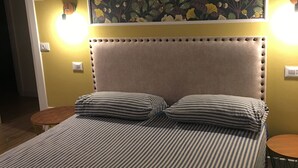 Un lit avec une literie à rayures, une tête de lit capitonnée et une décoration murale à motifs floraux au-dessus.