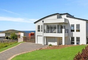 Una moderna casa a due piani con garage, vialetto in pietra e vista sul mare.