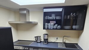 Una cocina compacta con tragaluz, estufa integrada, cafetera y lavamanos.