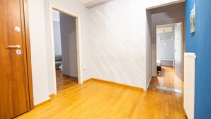 A hallway with wooden flooring, white walls, and a blue accent wall. - Egnatia Central Spacious 3 Bd Apt (Thessaloniki)