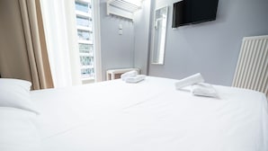 A hotel room with a large bed, a flat-screen TV mounted on the wall, and a window with curtains. - Egnatia Central Spacious 3 Bd Apt (Thessaloniki)