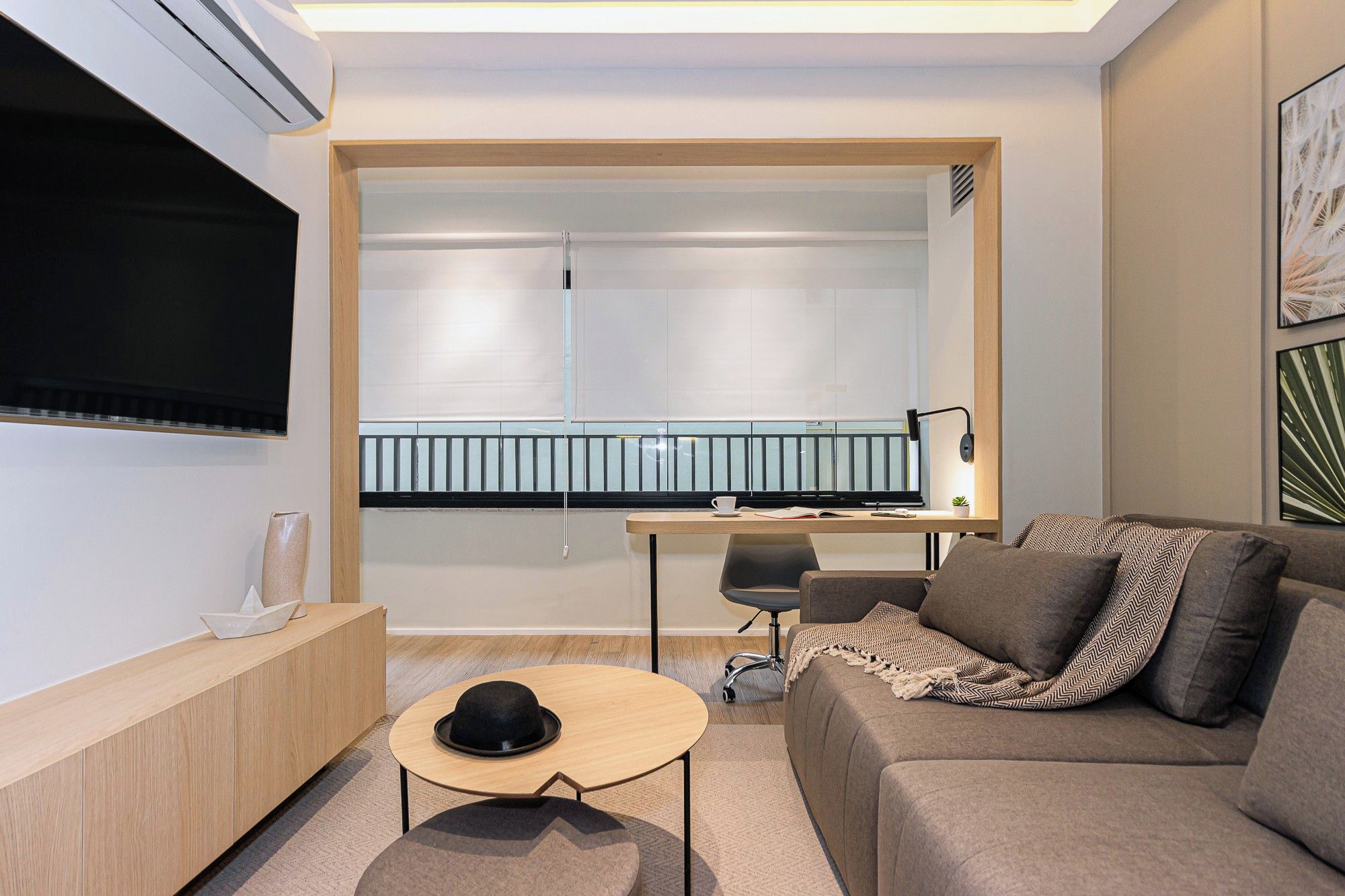 Una sala de estar moderna con una televisión de pantalla plana, un sofá, una mesa de centro y un escritorio con una silla.
