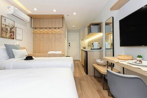 A hotel room with a bed, a desk, a kitchenette, and a TV. - House Of Charlie Apartments Pinheiros - Soft Opening (São Paulo)