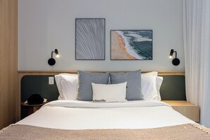 A hotel room with a bed, two wall-mounted lamps, and two framed pictures. - House Of Charlie Apartments Pinheiros - Soft Opening (São Paulo)