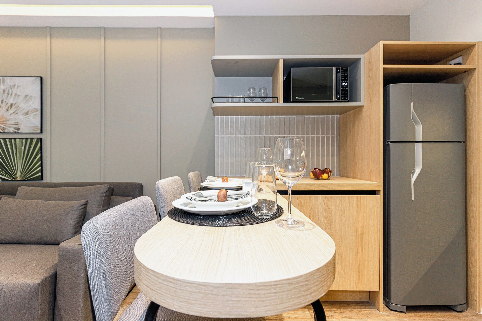 A modern kitchen with a microwave, a refrigerator, and a dining area with a table set for two.