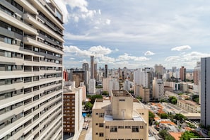 A high-rise building with multiple balconies and a cityscape in the background.