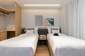 A hotel room with two beds, a desk, and a wardrobe. There are two framed pictures on the wall. - House Of Charlie Apartments Pinheiros - Soft Opening (São Paulo)