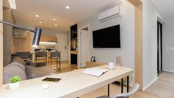 Um espaço de estar moderno com área de jantar, cozinha e TV na parede.