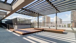 A rooftop terrace with a pergola, seating areas, and a view of surrounding buildings. - House of Charlie Pinheiros (São Paulo)