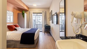 A hotel room with a bed, a desk, a chair, a mirror, and a hairdryer. - House of Charlie Pinheiros (São Paulo)