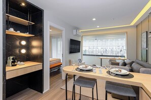 A modern kitchen with a dining area, a TV mounted on the wall, and a balcony with a view. - House Of Charlie Apartments Pinheiros - Soft Opening (São Paulo)