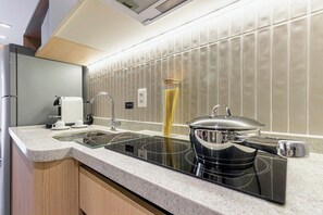 A modern kitchen with a built-in stove, a coffee machine, and a tall glass container of pasta. - House Of Charlie Apartments Pinheiros - Soft Opening (São Paulo)