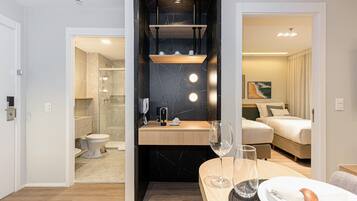 A modern hotel room with a bathroom, a dining area, and a bedroom.
