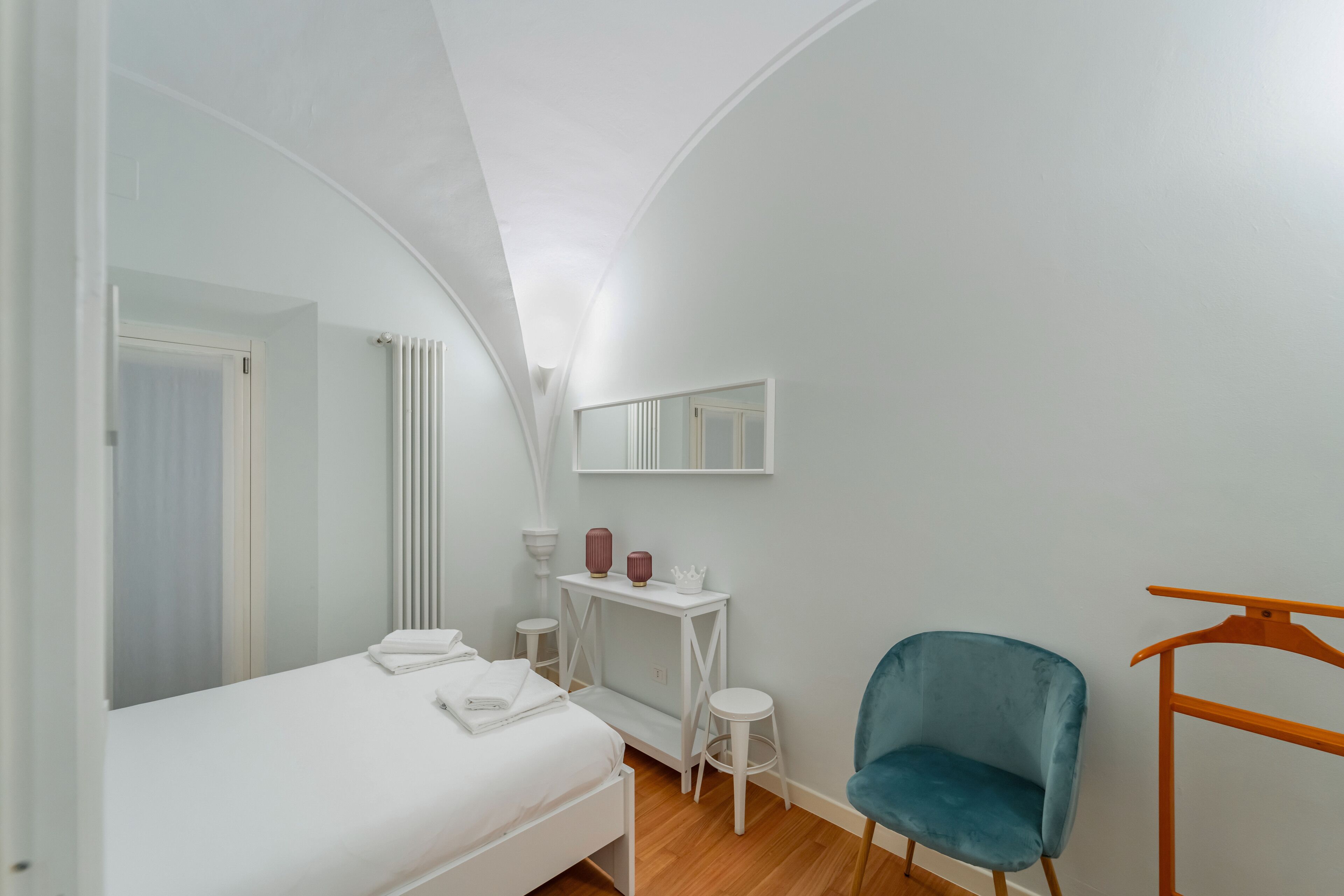 A modern bedroom with a bed, a vanity table, a chair, and a hanging rack.
