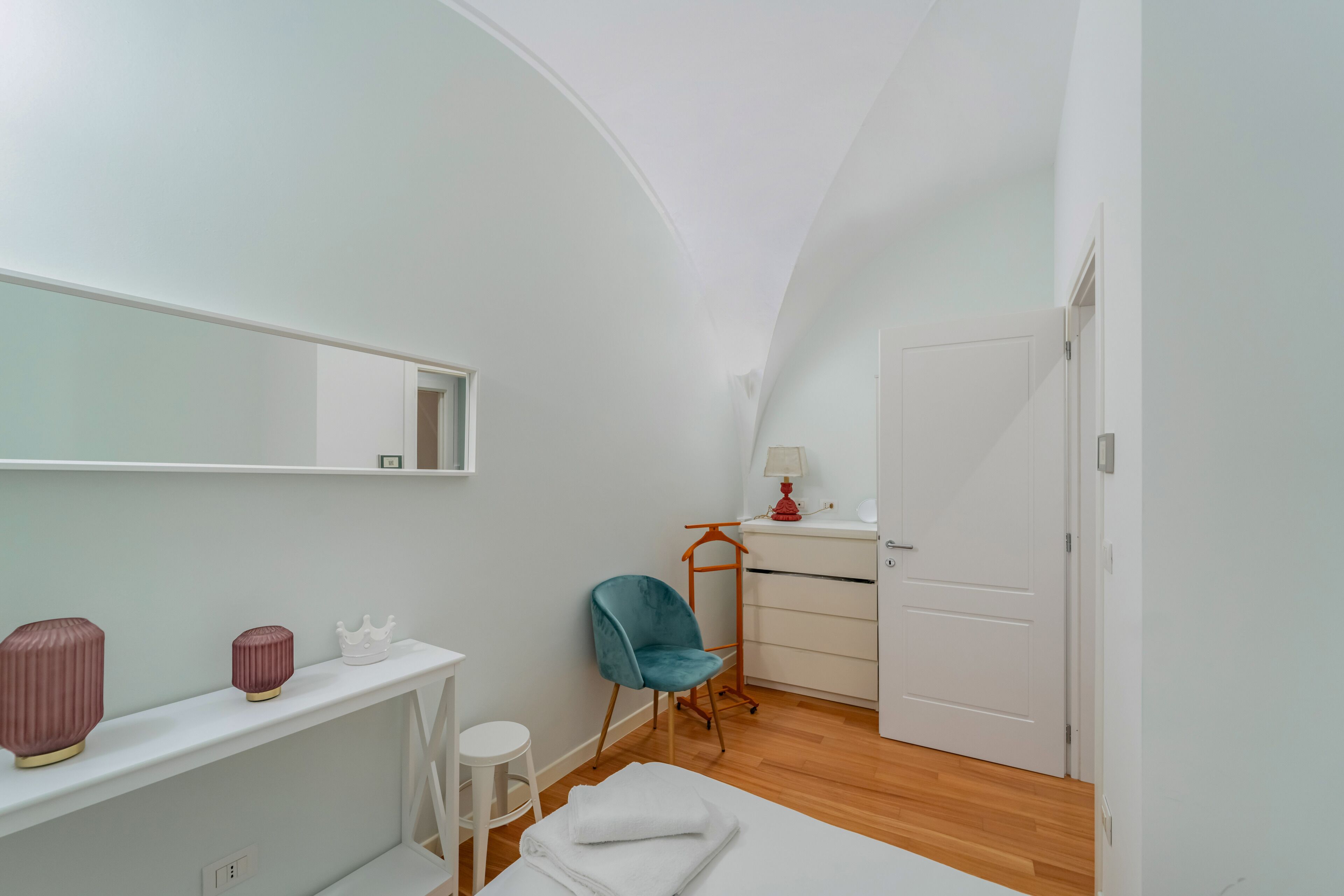 Une chambre avec un plafond en pente, un lit, une chaise, un bureau et une armoire.