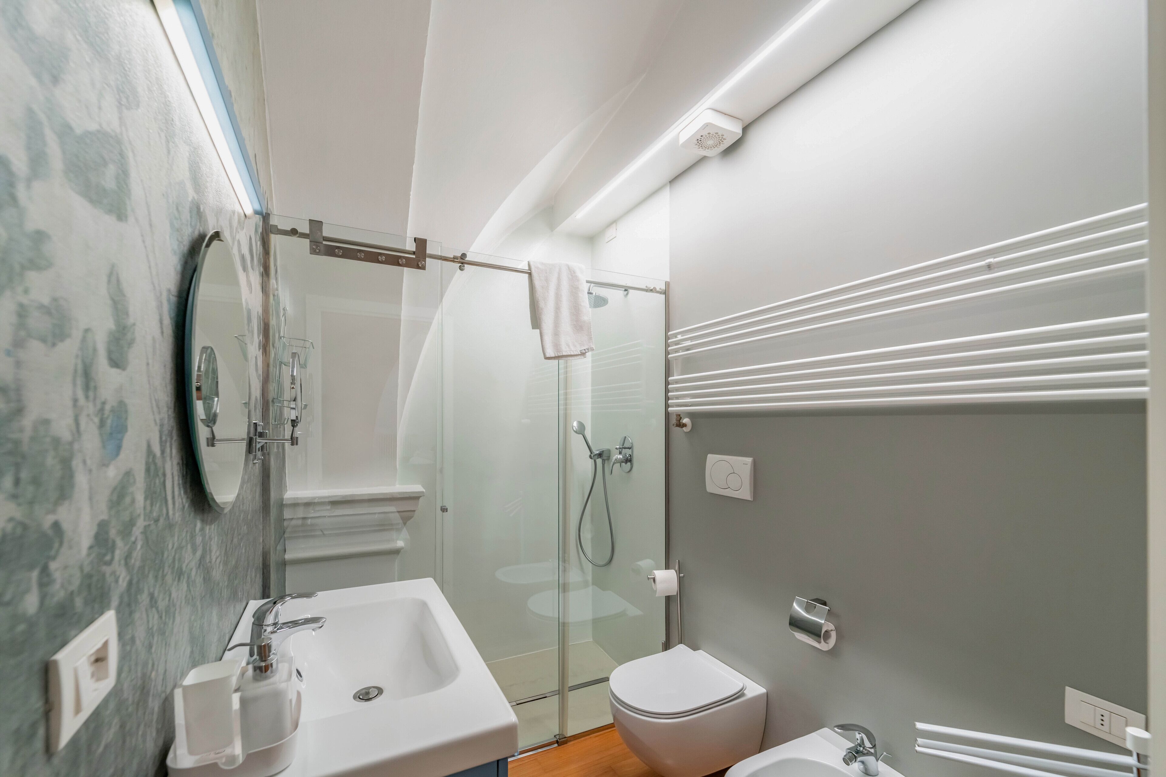 A modern bathroom with a glass shower enclosure, a white sink, and a toilet.