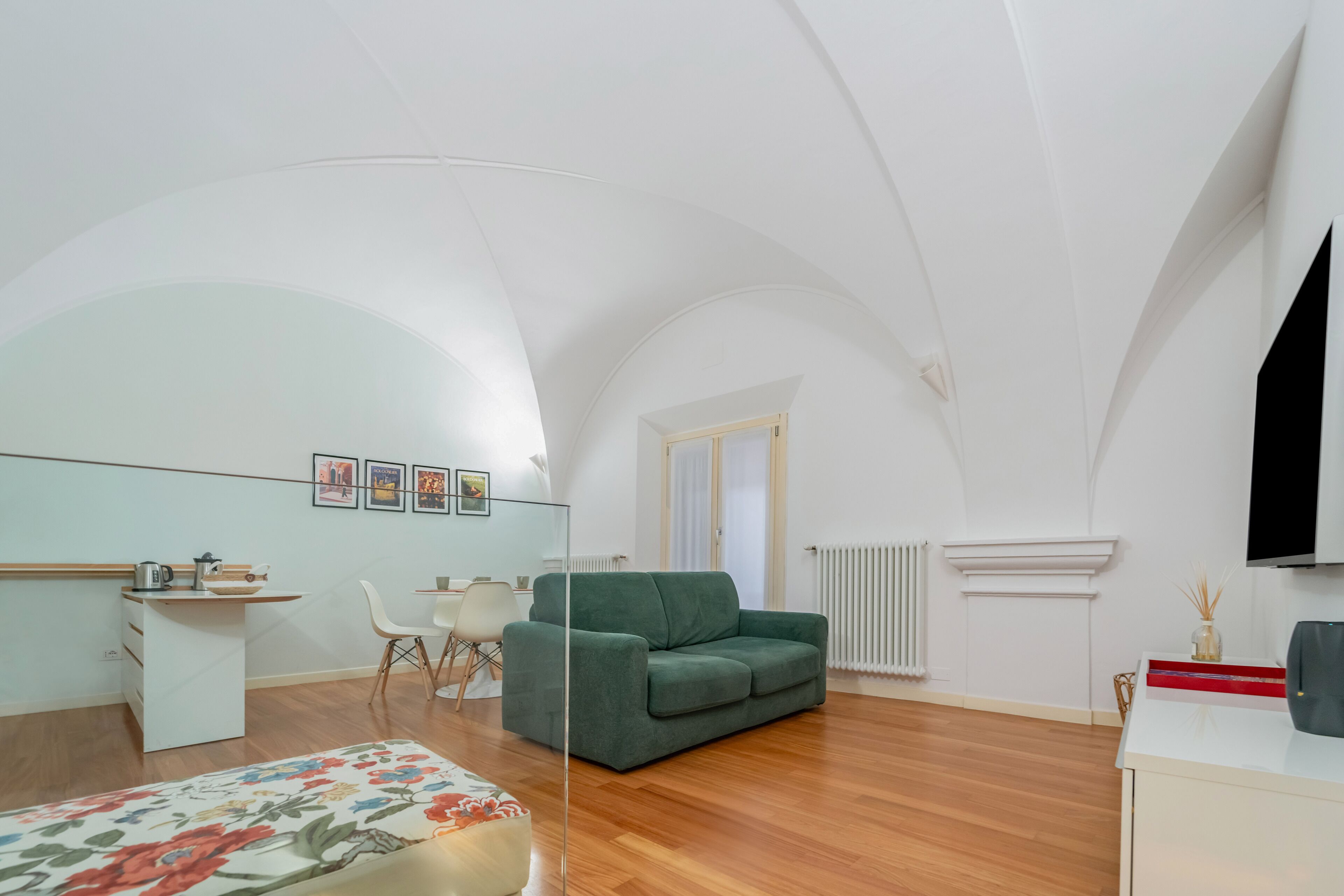 Una sala moderna con un sofá verde, una mesita blanca y un otoman con estampado floral.