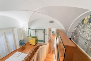 Ein geräumiges Zimmer mit Holzboden, einer Treppe, einem Bett, einem Schreibtisch und einem Kleiderschrank.