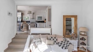 Un dormitorio con cama, mesita de noche, espejo y vista a una cocina y comedor.