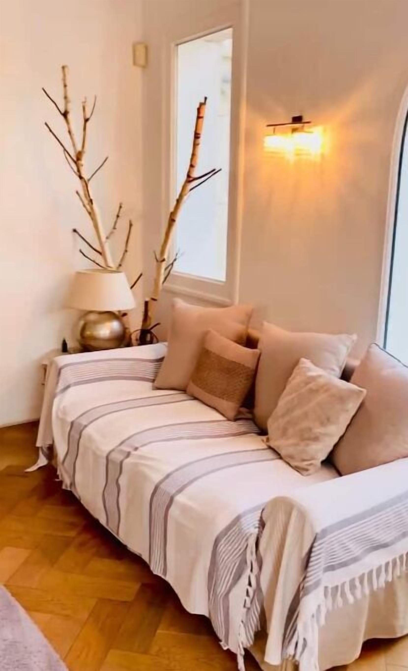 A cozy bedroom with a bed, pillows, a lamp, and a window.