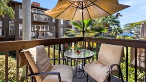 A balcony with two chairs, a table, and a large umbrella.