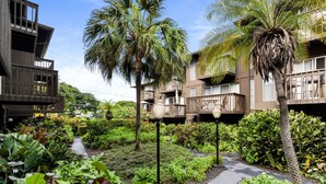 A hotel with multiple balconies, lush greenery, and a well-maintained garden.