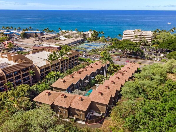 A resort with multiple buildings, a swimming pool, and a view of the ocean. - Malia Kai#5: Beautiful Townhome in Heart of Kona Town: Walk to everything! (Kailua Kona)