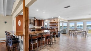 A modern kitchen with a large island, bar stools, and a view of the outdoors. - Lagoon Front | Boat Dock & Fishing Pier | Sleeps 12 (Gulf Shores)
